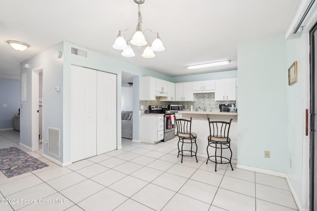 kitchen with decorative backsplash, a breakfast bar area, stainless steel appliances, a chandelier, and white cabinetry