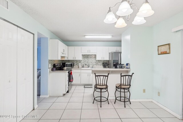 kitchen featuring backsplash, a kitchen breakfast bar, white cabinetry, pendant lighting, and stainless steel appliances