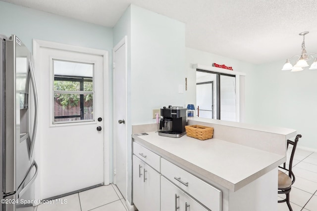 kitchen with kitchen peninsula, stainless steel fridge, white cabinets, a kitchen breakfast bar, and pendant lighting