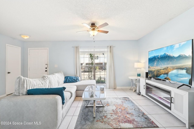 living room featuring ceiling fan, a textured ceiling, and light tile patterned floors