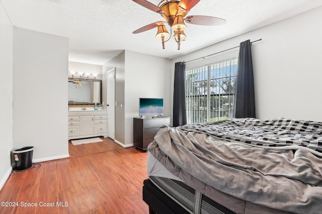 bedroom featuring light hardwood / wood-style flooring, a textured ceiling, ensuite bath, and ceiling fan