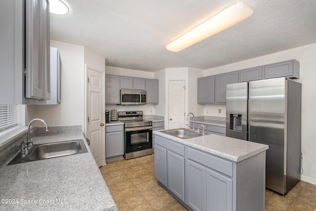 kitchen featuring gray cabinetry, sink, a kitchen island, and stainless steel appliances