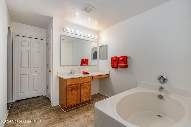 bathroom with vanity, a bath, and a textured ceiling