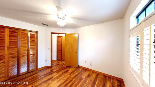 unfurnished bedroom with wood-type flooring, ceiling fan, and a closet