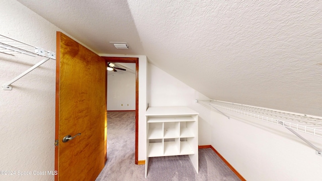 spacious closet featuring vaulted ceiling, light carpet, and ceiling fan