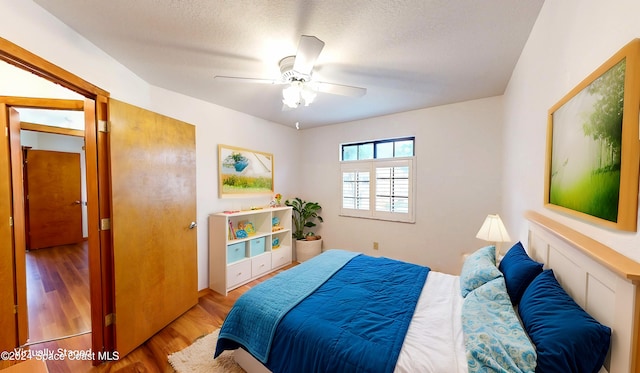 bedroom featuring ceiling fan, a textured ceiling, and light wood-type flooring