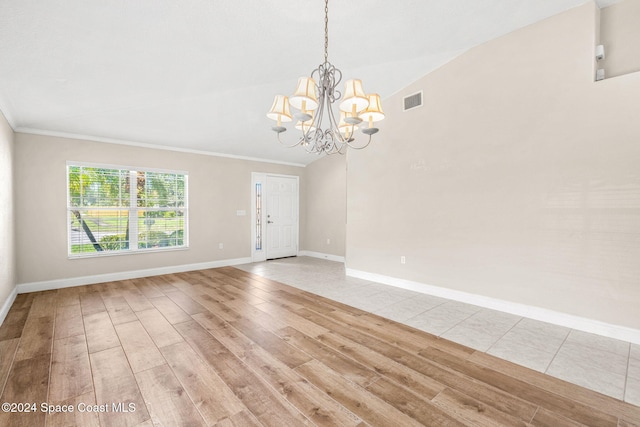 unfurnished room featuring light hardwood / wood-style floors, an inviting chandelier, crown molding, and vaulted ceiling