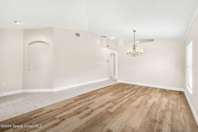 unfurnished room featuring light hardwood / wood-style floors, a notable chandelier, and vaulted ceiling