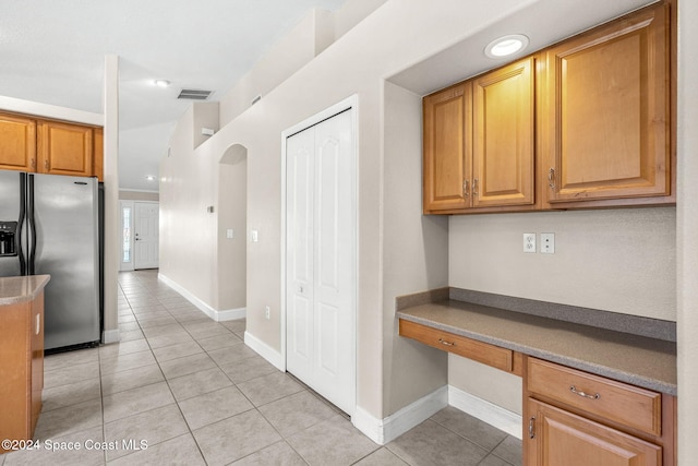 kitchen featuring built in desk, stainless steel fridge, and light tile patterned floors