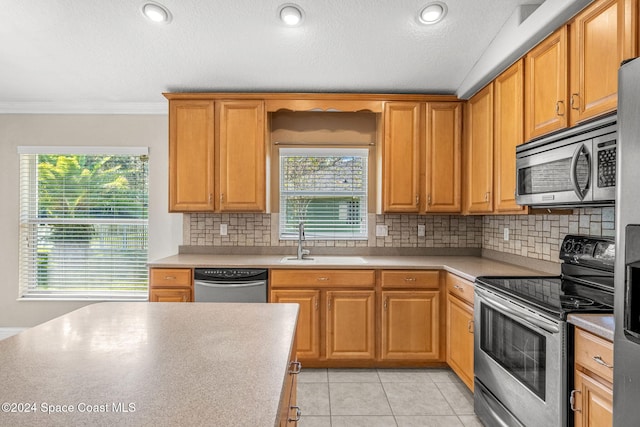 kitchen with tasteful backsplash, appliances with stainless steel finishes, light tile patterned flooring, sink, and ornamental molding