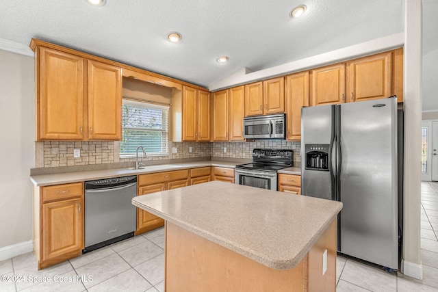 kitchen featuring a kitchen island, stainless steel appliances, sink, vaulted ceiling, and light tile patterned flooring