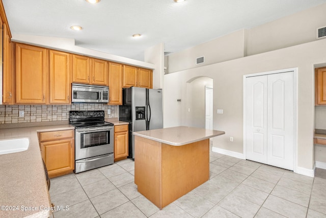 kitchen with a kitchen island, appliances with stainless steel finishes, backsplash, and light tile patterned flooring