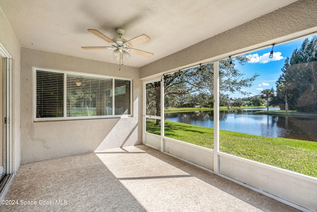 unfurnished sunroom with a water view and ceiling fan