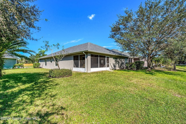 rear view of property featuring a yard and a sunroom