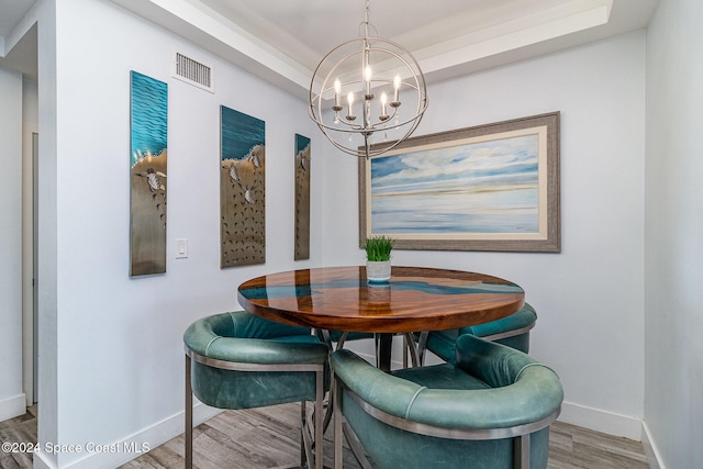 dining room with an inviting chandelier, hardwood / wood-style floors, and a tray ceiling