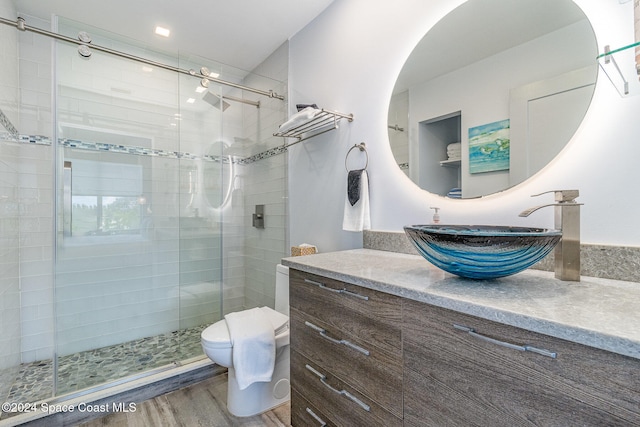 bathroom featuring vanity, hardwood / wood-style floors, a shower with shower door, and toilet