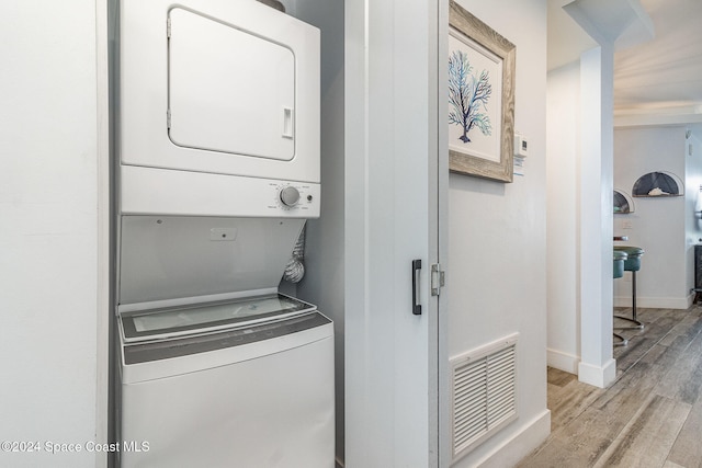 clothes washing area featuring stacked washing maching and dryer and light wood-type flooring