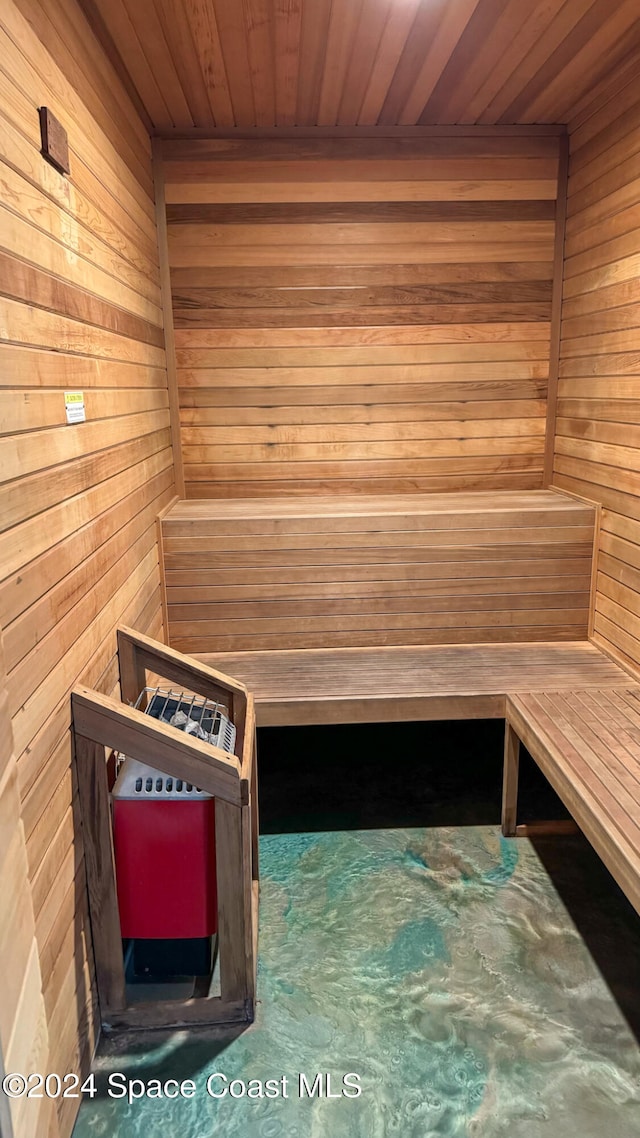 view of sauna / steam room with wooden walls, wooden ceiling, and concrete flooring