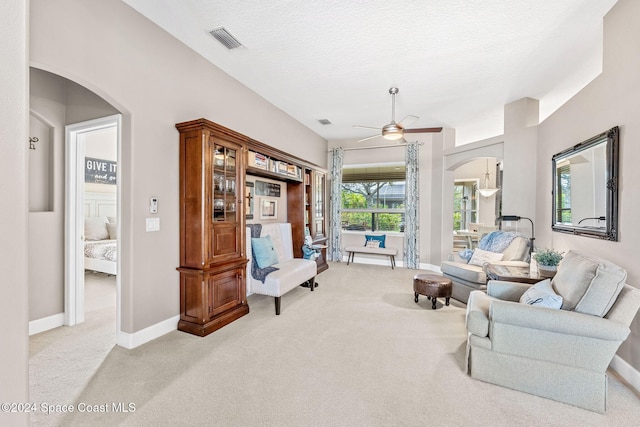 carpeted living room with ceiling fan and a textured ceiling