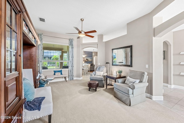 sitting room with a textured ceiling, light colored carpet, and ceiling fan