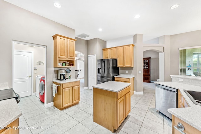 kitchen with light brown cabinets, appliances with stainless steel finishes, light tile patterned floors, and a kitchen island