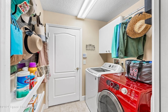 laundry area featuring washing machine and clothes dryer, cabinets, a textured ceiling, and light tile patterned floors