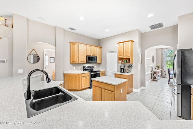 kitchen with light tile patterned flooring, a kitchen island, appliances with stainless steel finishes, light brown cabinetry, and sink