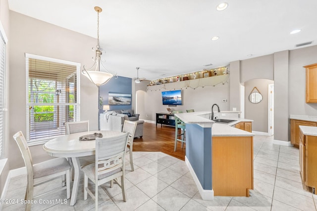 kitchen featuring pendant lighting, a kitchen island with sink, sink, and light tile patterned flooring