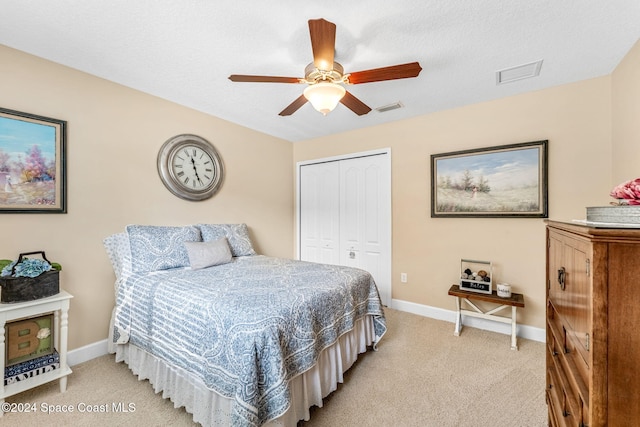 bedroom with ceiling fan, light carpet, a closet, and a textured ceiling