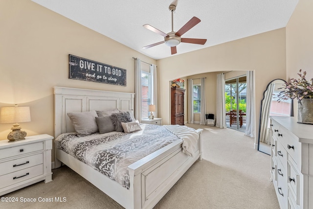 carpeted bedroom with ceiling fan, access to exterior, and a textured ceiling