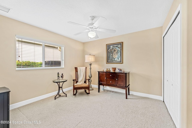 sitting room featuring a textured ceiling, light colored carpet, and ceiling fan