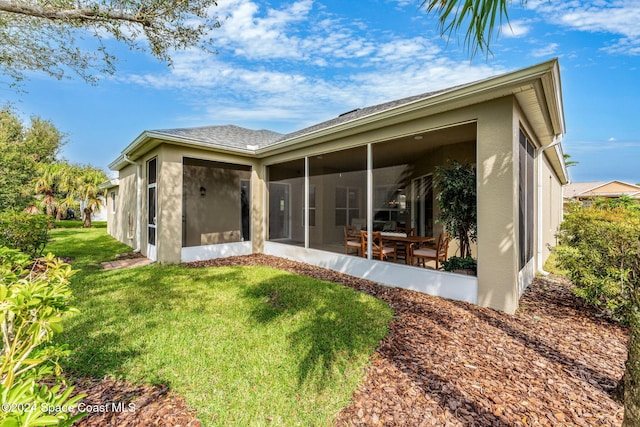 rear view of property with a lawn and a sunroom