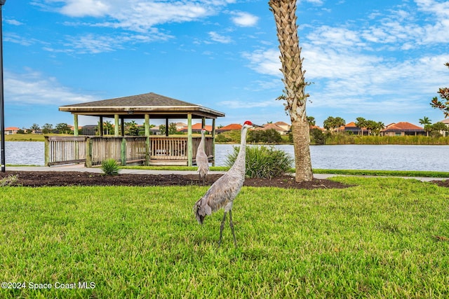 dock area with a gazebo, a water view, and a yard