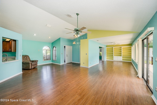 unfurnished living room featuring sink, vaulted ceiling, a textured ceiling, hardwood / wood-style flooring, and ceiling fan