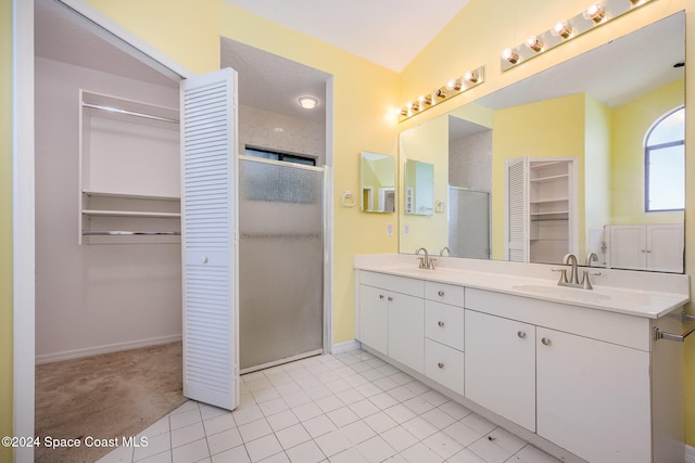 bathroom with lofted ceiling, vanity, tile patterned flooring, and walk in shower