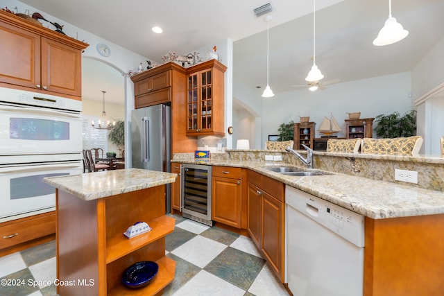 kitchen featuring sink, beverage cooler, an island with sink, decorative light fixtures, and white appliances