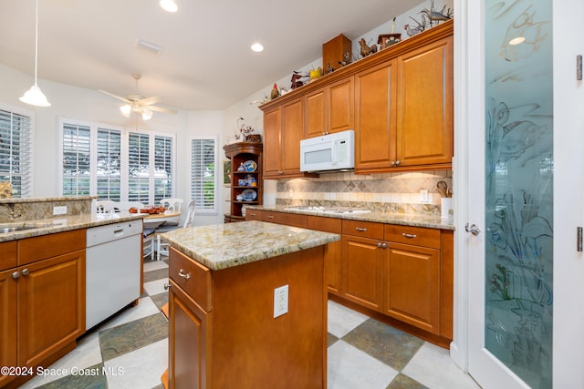 kitchen featuring a center island, white appliances, hanging light fixtures, ceiling fan, and tasteful backsplash