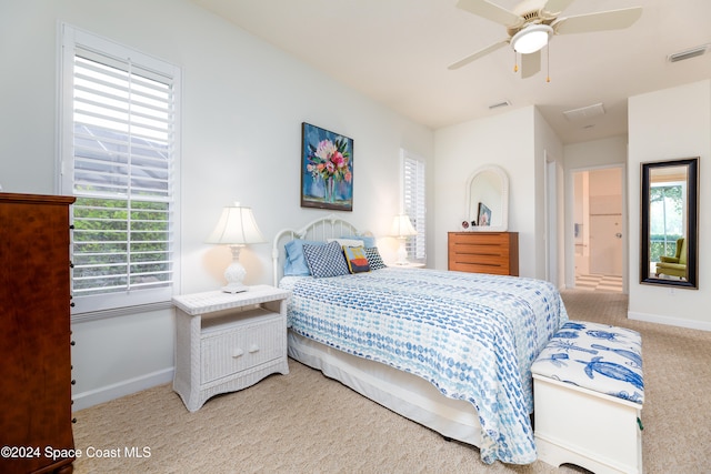 carpeted bedroom with connected bathroom, multiple windows, and ceiling fan