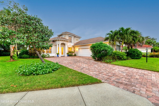 mediterranean / spanish-style home featuring a garage and a front lawn