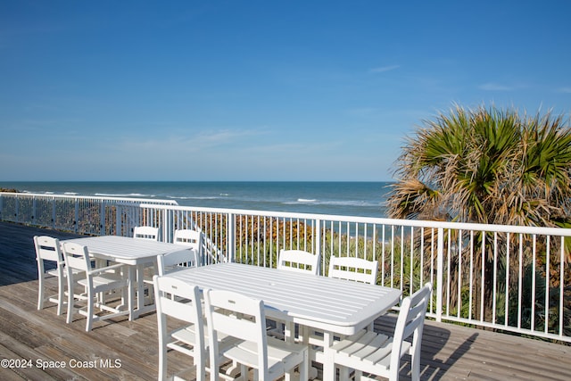 wooden deck featuring a beach view and a water view