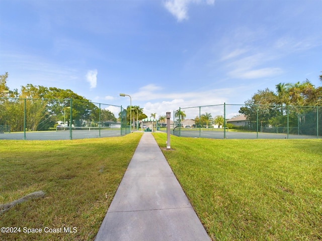 surrounding community featuring tennis court and a lawn