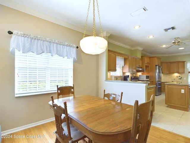 dining room with ceiling fan, ornamental molding, and light wood-type flooring