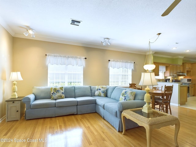 living room with ornamental molding, light wood-type flooring, and ceiling fan