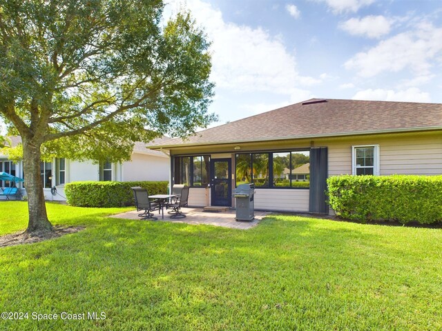 rear view of house featuring a patio area, a yard, and a sunroom