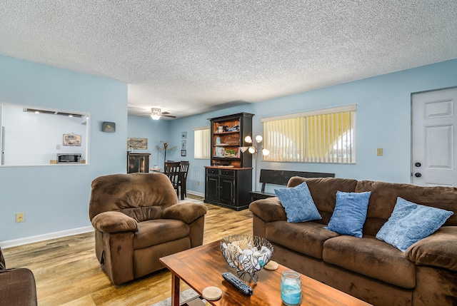 living room featuring a healthy amount of sunlight, a textured ceiling, hardwood / wood-style flooring, and ceiling fan