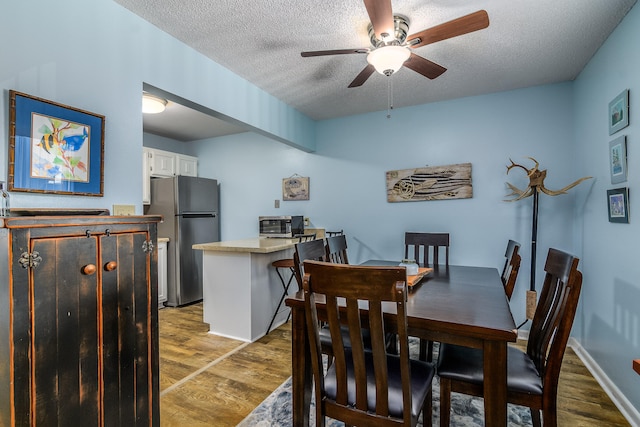 dining room featuring a textured ceiling, dark hardwood / wood-style floors, and ceiling fan