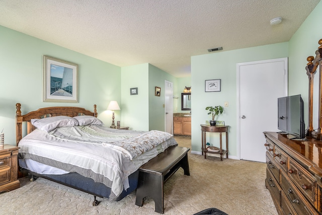 carpeted bedroom featuring ensuite bathroom and a textured ceiling