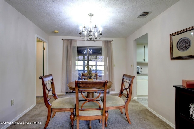 carpeted dining room featuring an inviting chandelier and a textured ceiling