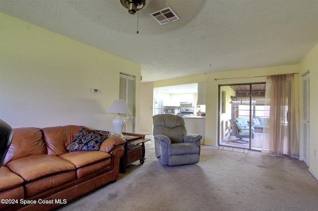 carpeted living room featuring a textured ceiling and ceiling fan