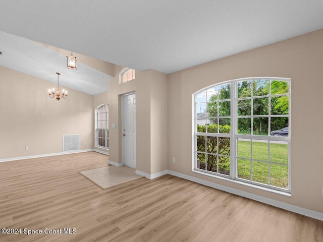 unfurnished room featuring light hardwood / wood-style flooring, a notable chandelier, and lofted ceiling